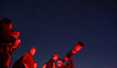 A child looks through a telescope at night
