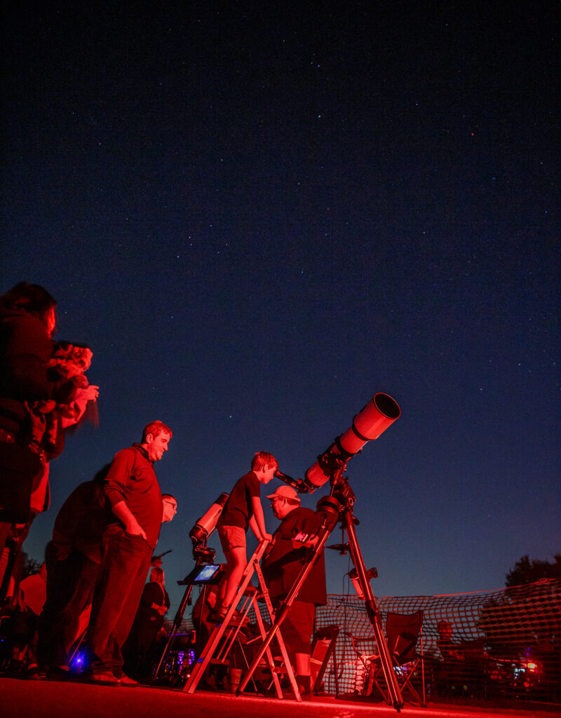 A child looks through a telescope at night