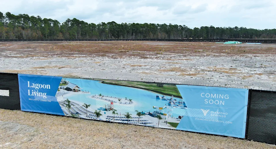 A banner hangs on the fence surrounding where the lagoon area will be built at Diamond Springs, Wednesday morning, February 11, 2026 in Jacksonville, Fla. Metro Development Group is developing the land near Cecil Airport. The lagoon concept is designed for kayaking and swimming, with amenities such as a swim-up bar, a floating obstacle course and a splash pad. [Doug Engle/Florida Times-Union]