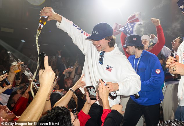 Jack Hughes is pictured sharing his beer with some onlookers in Miami with his brother, Quinn, standing behind him. The team was celebrating their gold medal victory at E11EVEN Miami