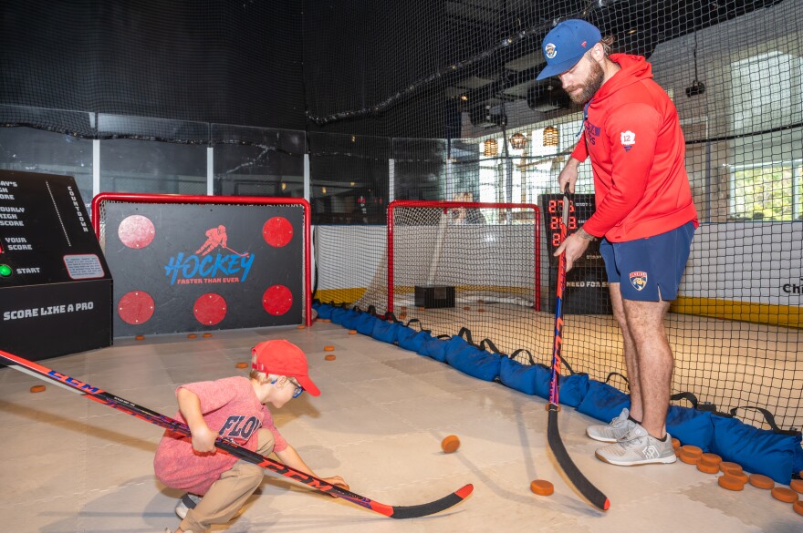 A man and a child set up hockey pucks to shoot on goal