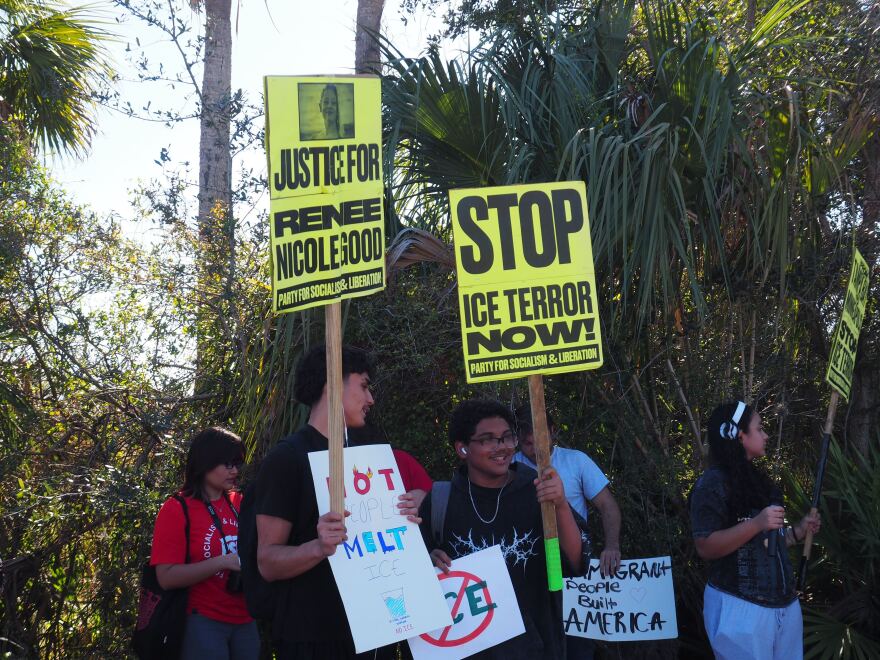 students hold signs while protesting against ICE