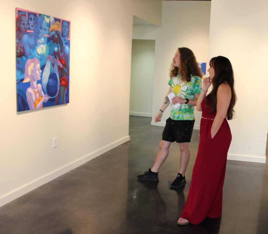 Alliance Gallery Manager Julio Julio Gonzalez Batista discusses Delgado painting with Director of Marketing & Communications Melissa DeHaven.