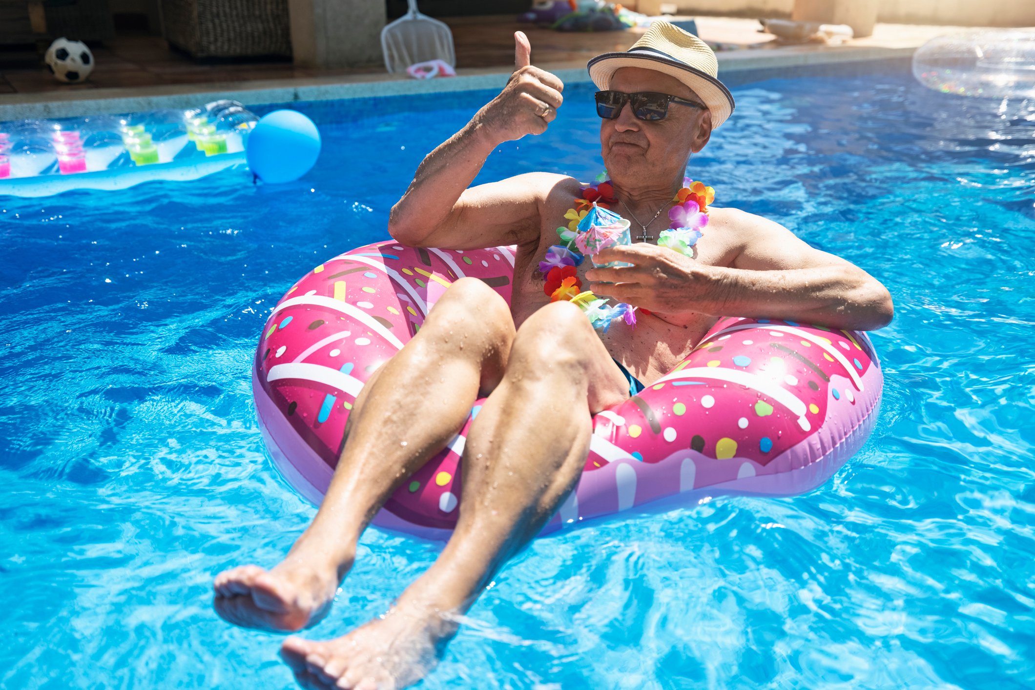 An older person in a floatation device in a swimming pool.