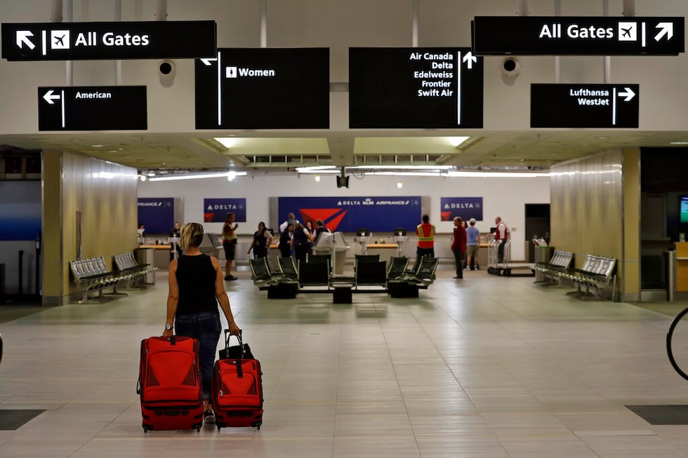 A passenger carries her luggage through a nearly deserted terminal at the Tampa International...