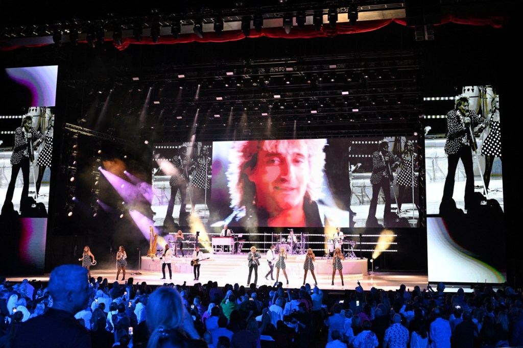 Photo of a stage with a big screen showing a Rod Stewart video