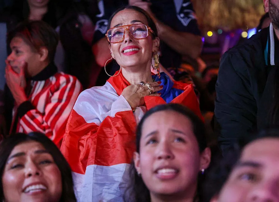 In the center, Tara Fougner, cannot hold her excitement while draped with a Puerto Rican flag as Bad Bunny starts his show. 