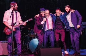 (L-R): Bentzi Marcus Shmully Marcus Rabbi Alter Korf Yechiel Jacobs and Rabbi Mendel Lebovics breaking into Chassidic dance on stage.