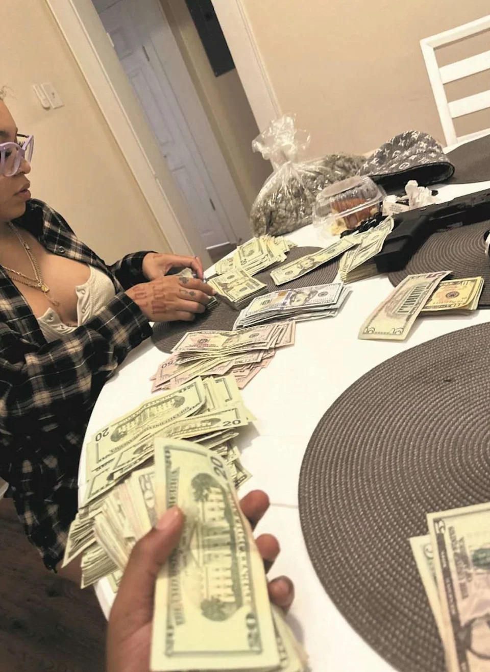 This photo of cash being counted on a table beside marijuana and a pistol was part of a federal drug conspiracy complaint filed in 2024 against a member of Nathaniel Hatcher's pot ring.