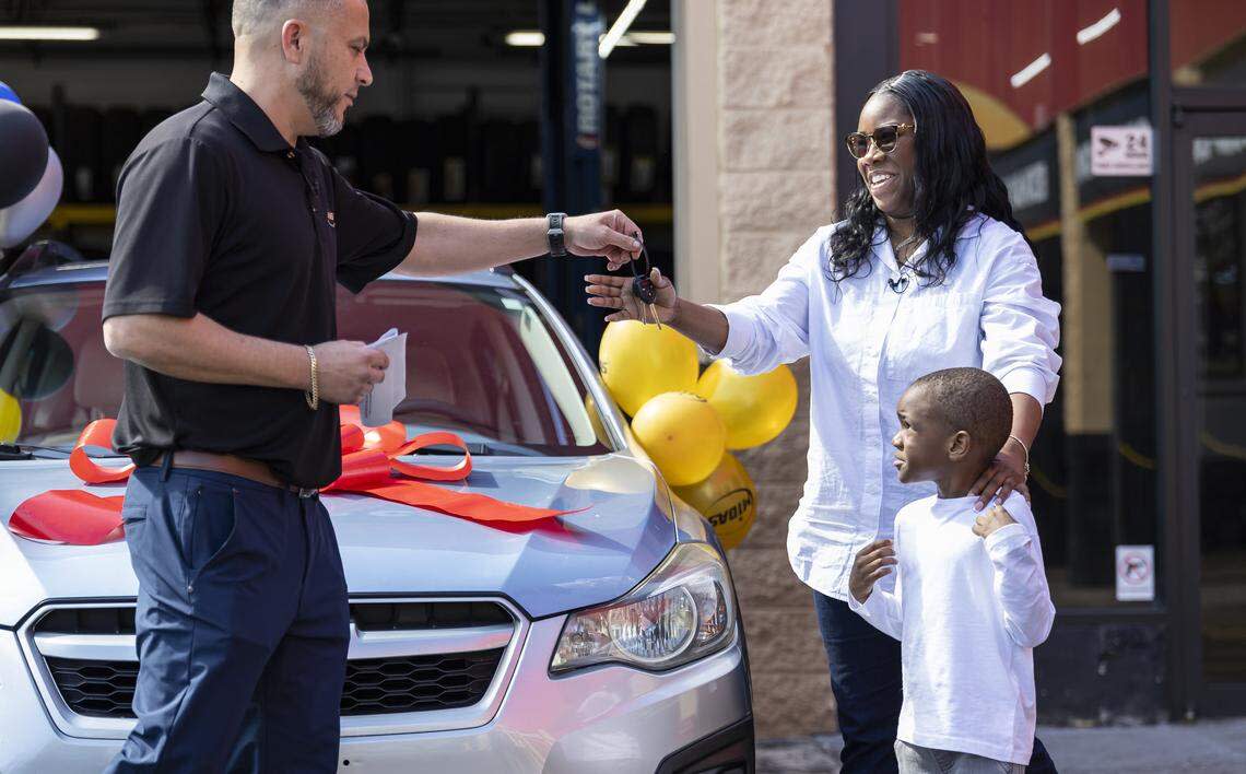 Renee King, 36, and her son Kingston Allen, 4, receive the keys to a free refurbished Subaru Impreza from Yoel Victores, 42, a franchise owner of a Midas in Fort Lauderdale. King, a single mom with two children, was forced to give up her previous car and relied entirely on public transportation to get to work.