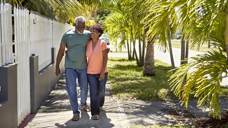 Retired couple walking along a street lined with palm trees