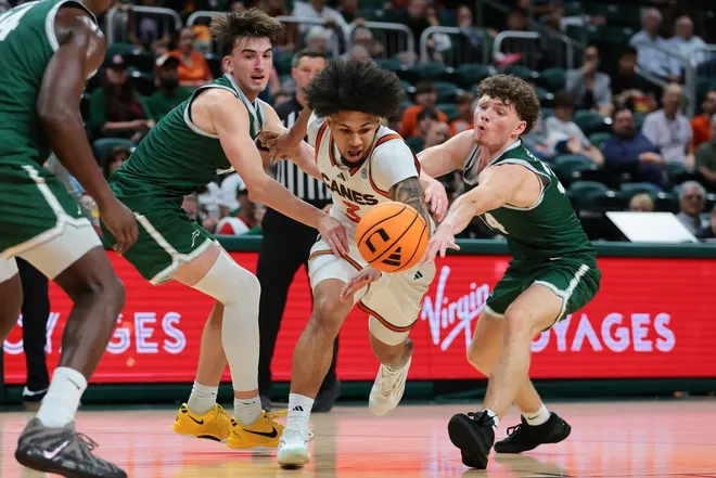 Nov 3, 2025; Coral Gables, Florida, USA; Miami Hurricanes guard Tre Donaldson (center) drives to the basket against Jacksonville Dolphins guard Hayden Wood (left) and guard Evan Sterck (34) during the second half at Watsco Center.