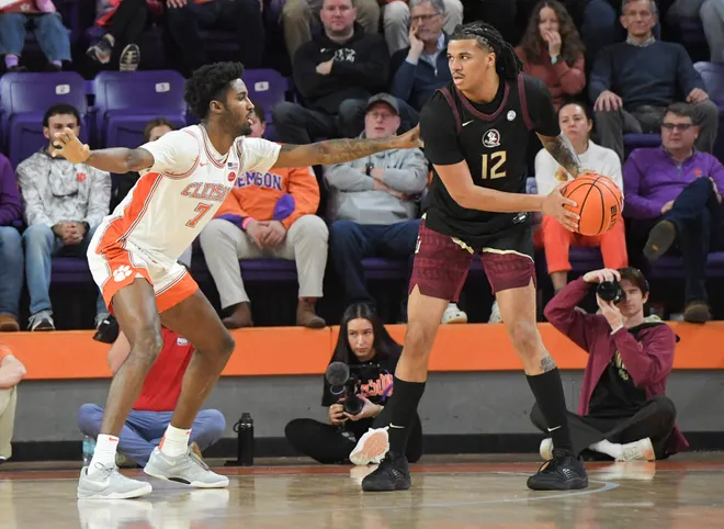 Jan 11, 2025; Clemson, South Carolina, USA; Florida State Seminoles forward Malique Ewin (12) controls the ball against Clemson Tigers forward Chauncey Wiggins (7) during the first half at Littlejohn Coliseum. Mandatory Credit: Ken Ruinard/USA TODAY Network via Imagn Images