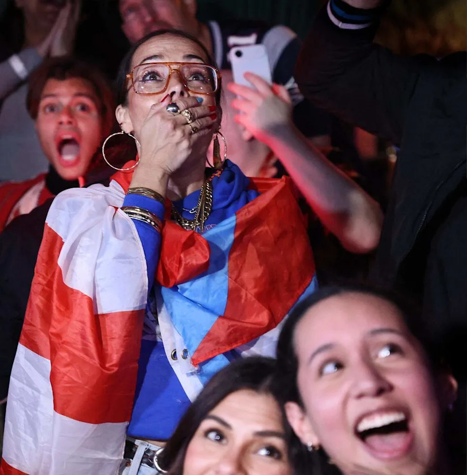 In the center, Tara Fougner, cannot hold her excitement while draped with a Puerto Rican flag as Bad Bunny starts his show. 