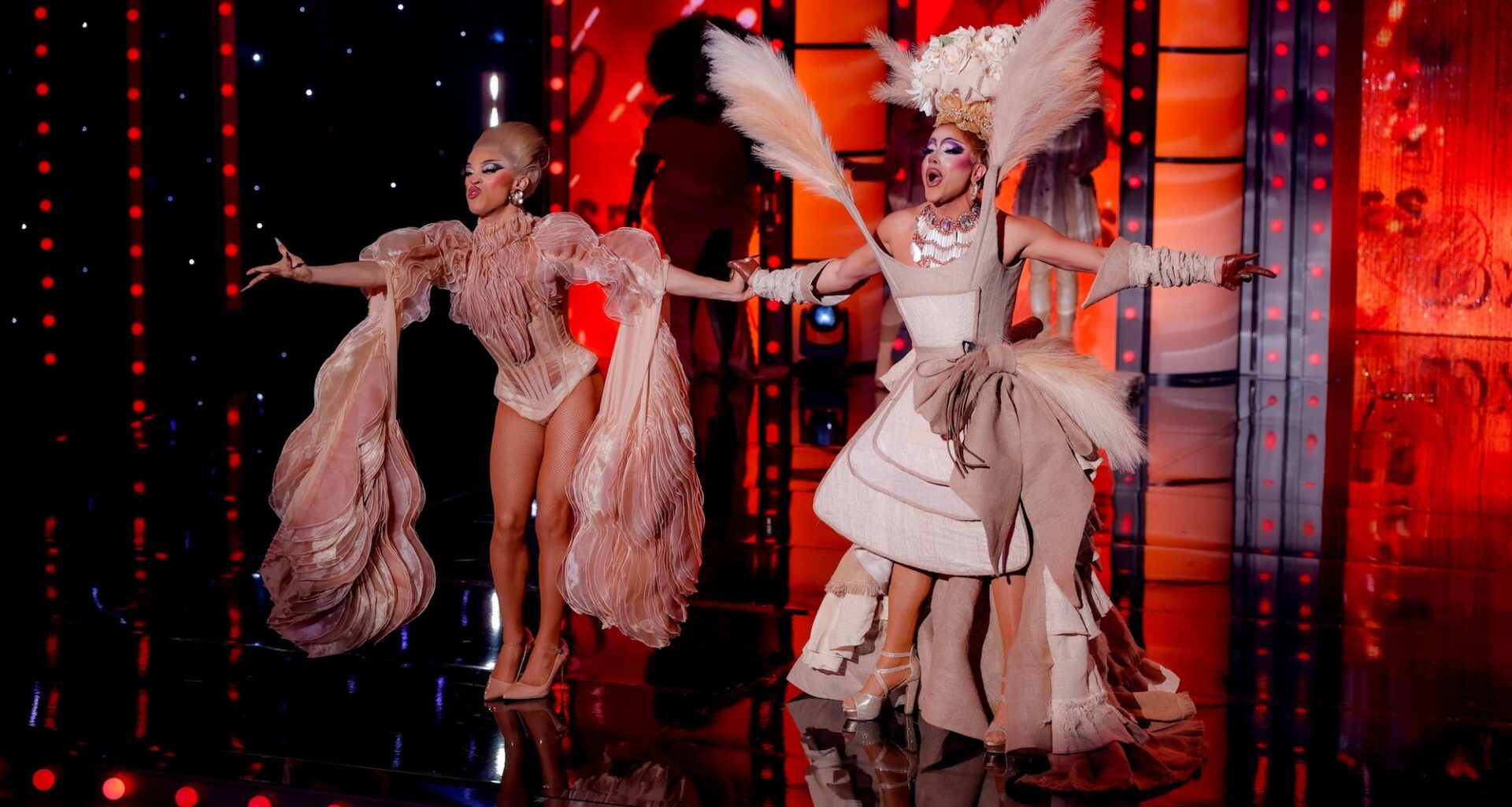 photo of two drag queens in architectural beige outfits and wigs performing on a stage