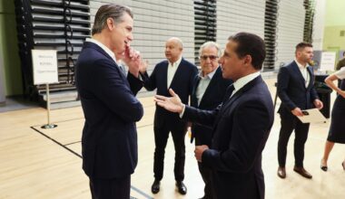 photo of California Gov. Gavin Newsom (left) and Alberto M. Carvalho (right) in conversation with several people standing behind them