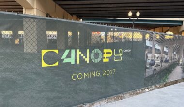 A green signs reads The Canopy Project Coming 2027, mounted to a fence underneath the elevated section of Interstate 4 in downtown Orlando. (Spectrum News/Keith Landry)