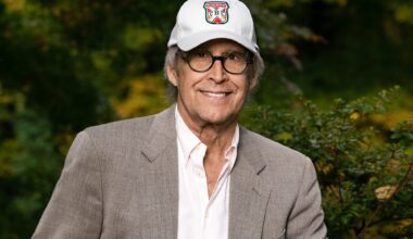 photo of comedian Chevy Chase wearing a baseball cap, white button-down, and blazer