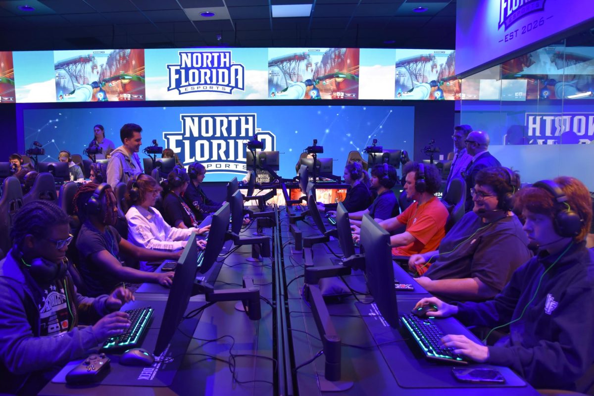 A dark room lit with blue LED lights, 10 people are on computers gaming.