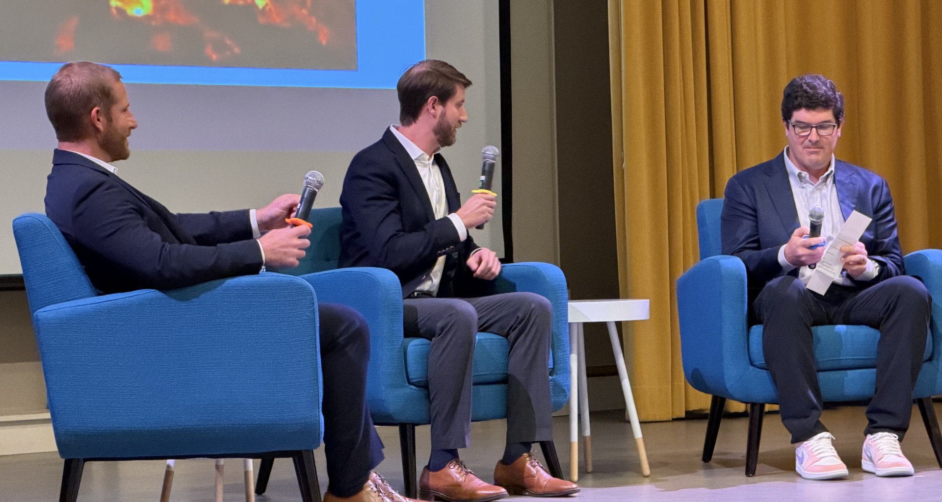 three seated men talking in a panel.
