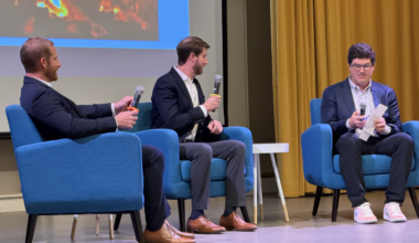 three seated men talking in a panel.