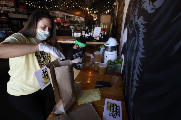 Juliana Calloway, owner of Black Rooster Taqueria in Orlando, and her son Ryder Calloway, then 7, package Margarita-grams during the pandemic in 2020. Black Rooster Taqueria The Margarita-gram concept allowed people to send drinks and good spirits to loved ones on lockdown. (Ricardo Ramirez Buxeda/ Orlando Sentinel)