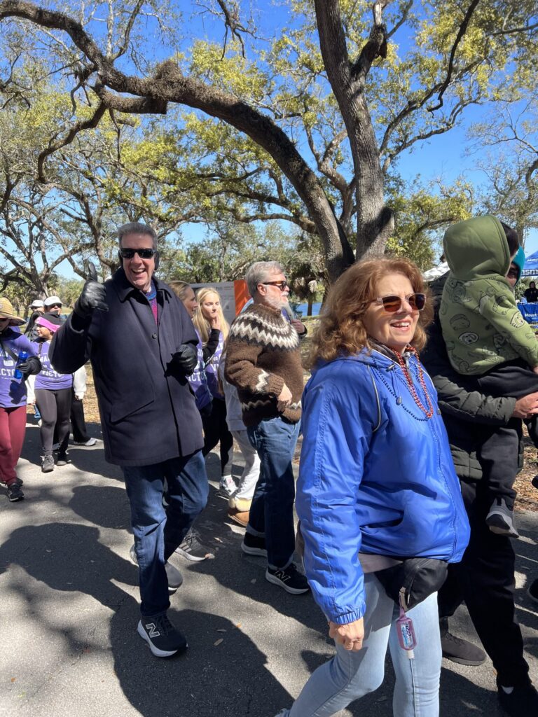 Marfan Foundation Board Chair Bert Medina in warm coat, sweater, and ear muffs gives a thumbs up at the South Florida Walk for Victory. 