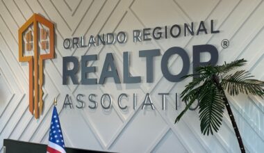 Black lettering and an orange key are shown on the Orlando Regional Realtor Association sign at the office's front desk.