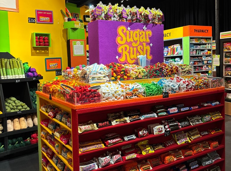 A brightly colored store display titled 'Sugar Rush' filled with fake candy and chocolate bars made entirely of felt.