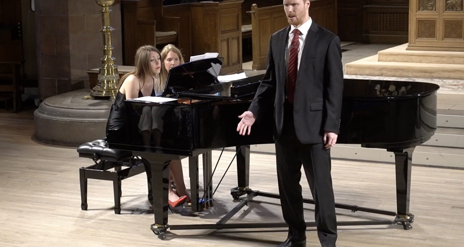 Photo of two women on stage playing piano and a opera singer