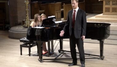 Photo of two women on stage playing piano and a opera singer