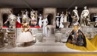 photo of ornate dresses on mannequins on a platform inside an art gallery