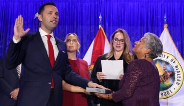 Bryan Calvo, 28, standing with his girlfriend, Melianni Terrero, Hialeah, and his mother, Edith Calvo, far right, is sworn in as mayor of Hialeah by Miami-Dade Circuit Judge Carmen Cabarga at the Milander Center on Monday, Jan. 12, 2026, in Hialeah.