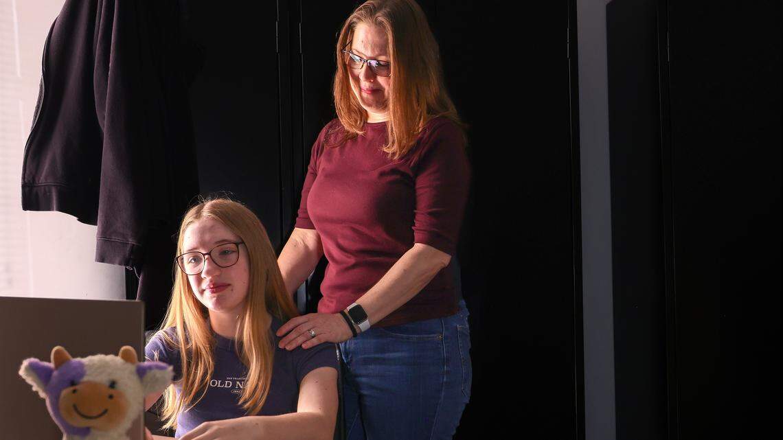 Christina Underwood, right, stands over her 13-year-old daughter Harper's shoulder as they recall her medical emergency and nearby hospitals rejecting her Florida Blue insurance coverage on Thursday, February 12, 2026, in Fort Lauderdale, Florida. The stuffedd colorful cow, left, was a gift from Christina to her daughter, and she travels with it often as a reminder of her mother's love and support.
