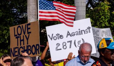 Demonstrators hold signs that read “LOVE THY NEIGHBOR” and “VOTE AGAINST 287(g)” during a press conference hosted by ACLU Florida, Florida Rising, The Florida Immigrant Coalition and Family Action Network Movement on Tuesday, June 17, 2025, in Miami.