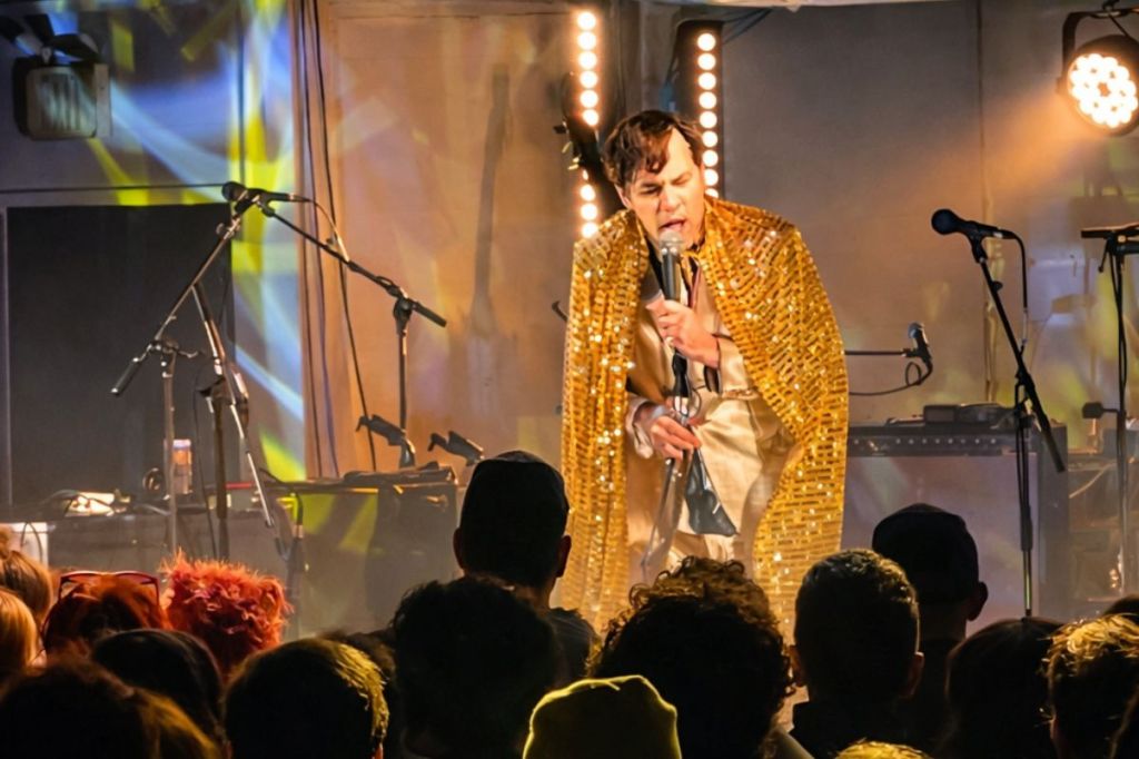 Photo of a performer on stage wearing a golden cape 
