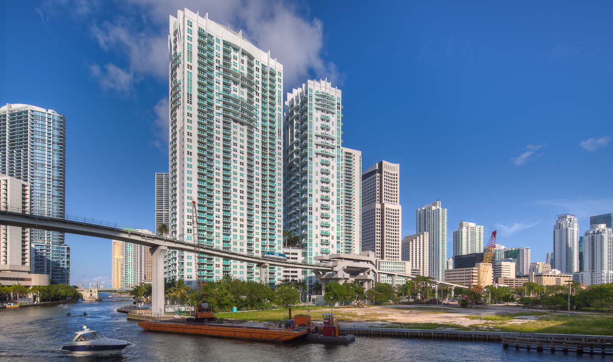 skyscrapers stand behind a waterway dotted with boats