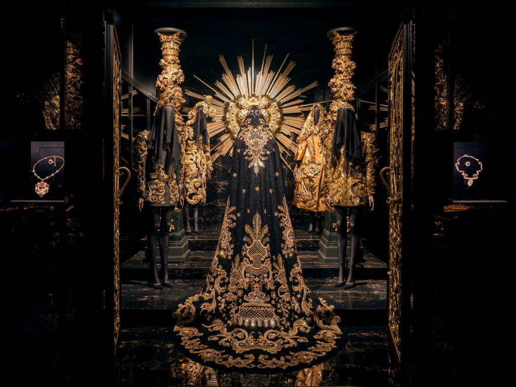 photo of an exhibition showing black clothes with gold embroidery inside a gallery