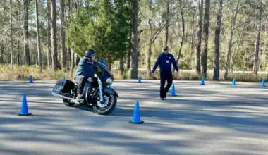 A motorcyclist weaves around blue cones during a motorcycle safety class.