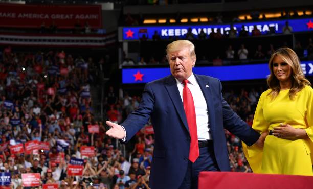 President Donald Trump looks on as First Lady Melania Trump...