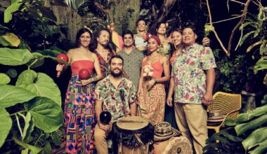 Photo of a band dressed in colorful colors posing in the middle of plants