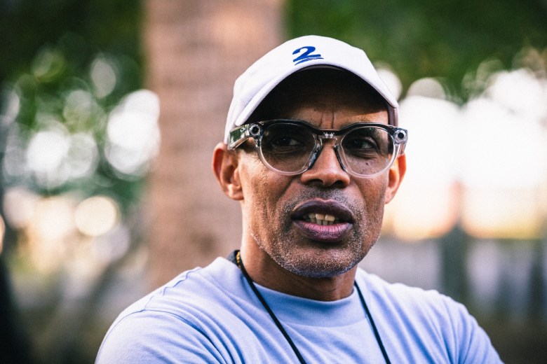 Olympic medalist Meb Keflezighi at Fred Ball Park in Tampa, Florida. The legendary American distance runner is pictured in a white hat and glasses during a Plant High School track team practice.