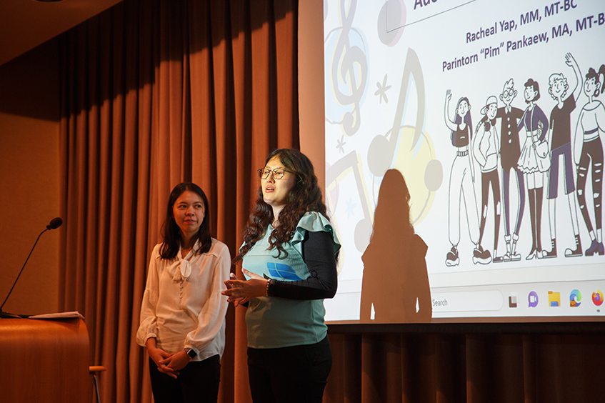 Two women present information on a stage.