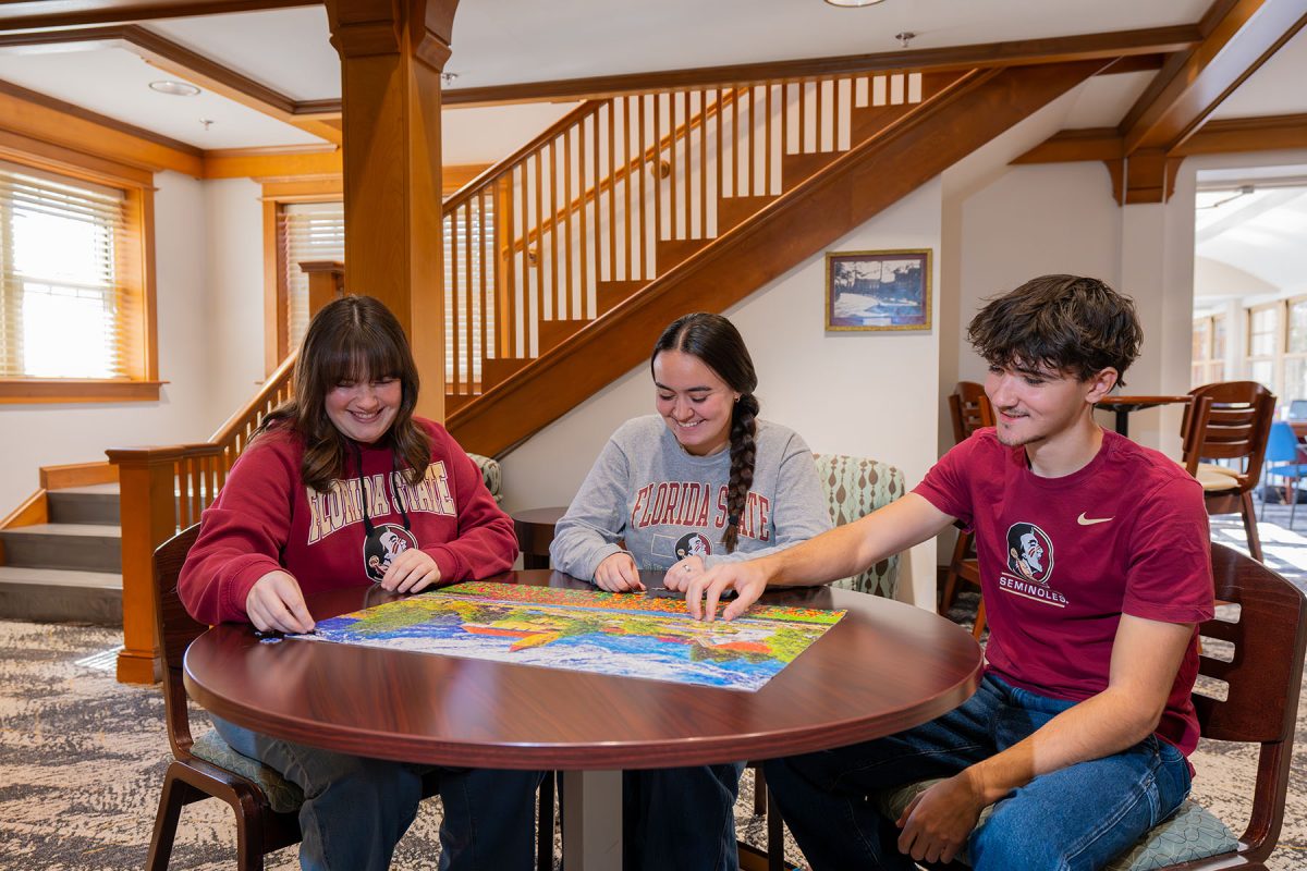 First-year students sit at a table and work together on a puzzle in Bryan Hall.