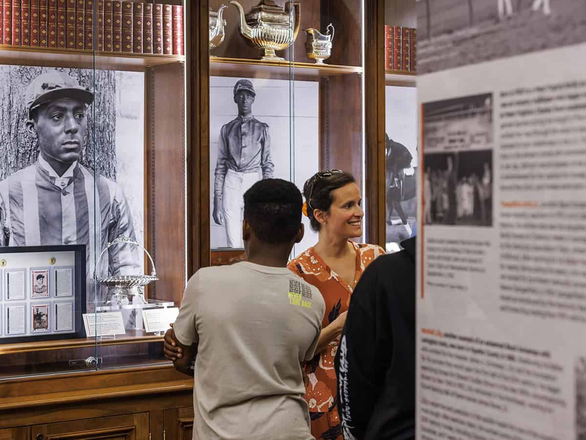 Onlookers walk through the traveling exhibition of The Heart of the Turf: Racing’s Black Pioneers. The exhibition showcases historical imagery, items, and information that explores African American history in Thoroughbred racing and examines how generations of Black professionals shaped the United States racing industry while facing systemic racism and exclusion. (Photo: ©Keeneland)