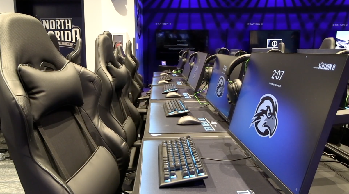 A room with 5 computers, black chairs and keyboards.