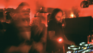 Blurred photo of two DJs under red lights