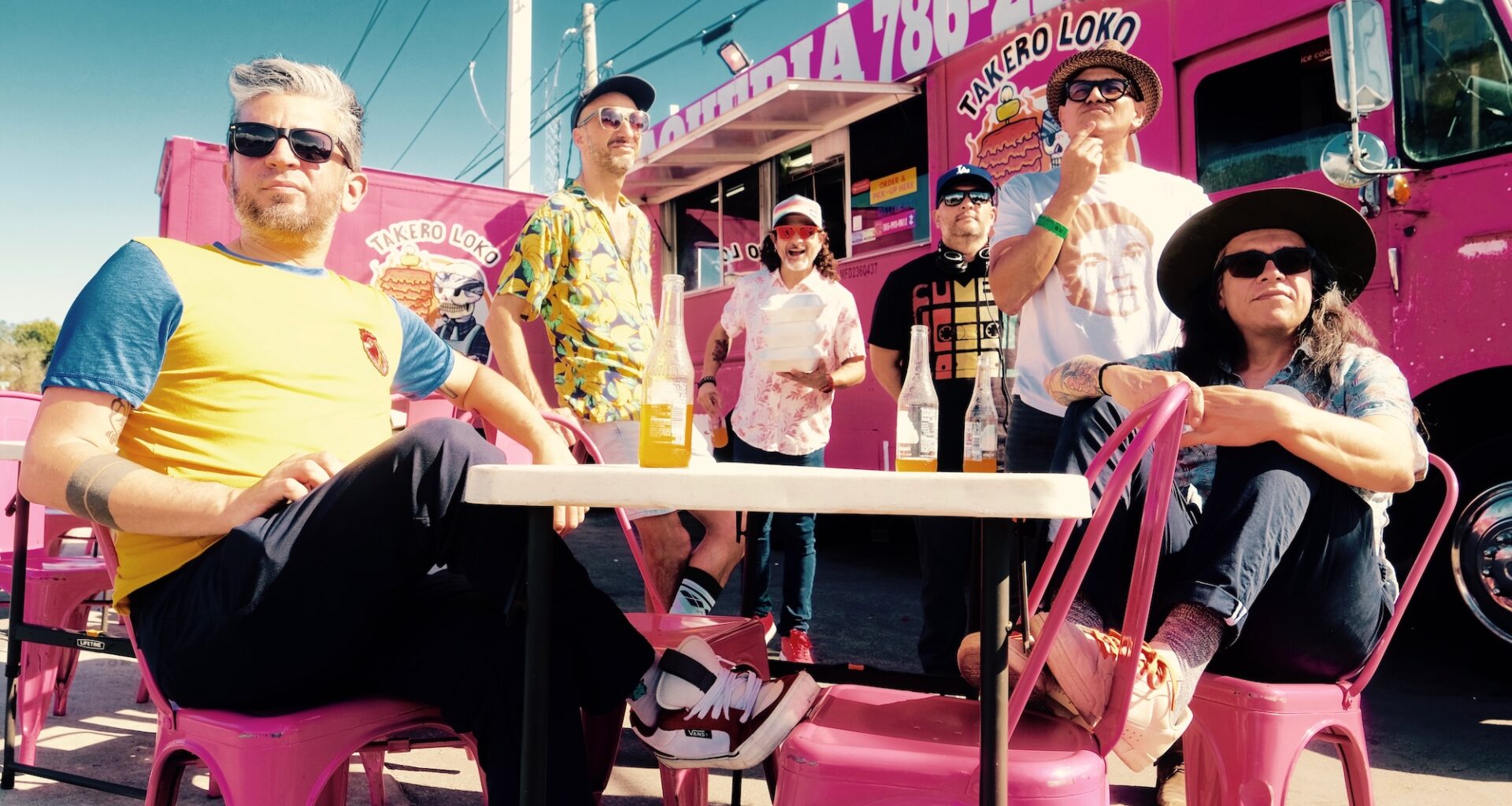 Photo of a group of men sitting by a pink food truck
