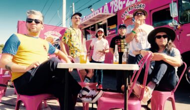 Photo of a group of men sitting by a pink food truck