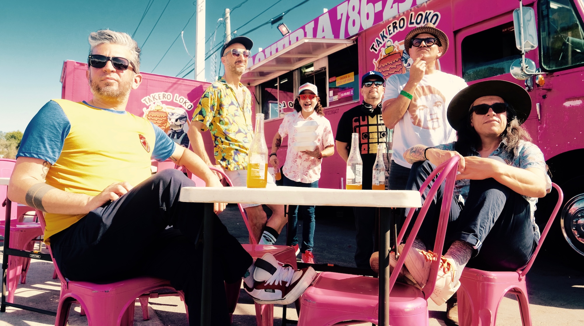 Photo of a group of men sitting by a pink food truck